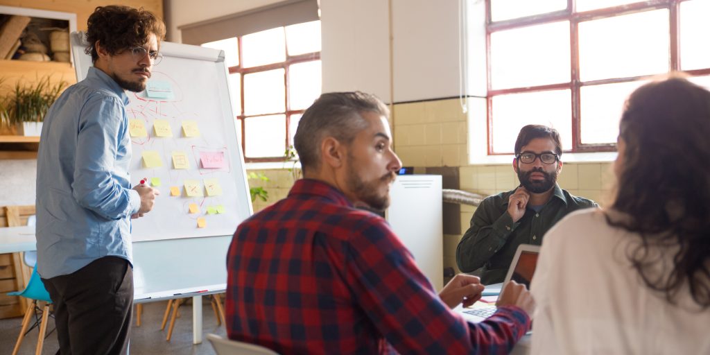 Startup team meeting and discussing ideas in boardroom. Business colleagues in casual working together in contemporary office space. Brainstorming concept